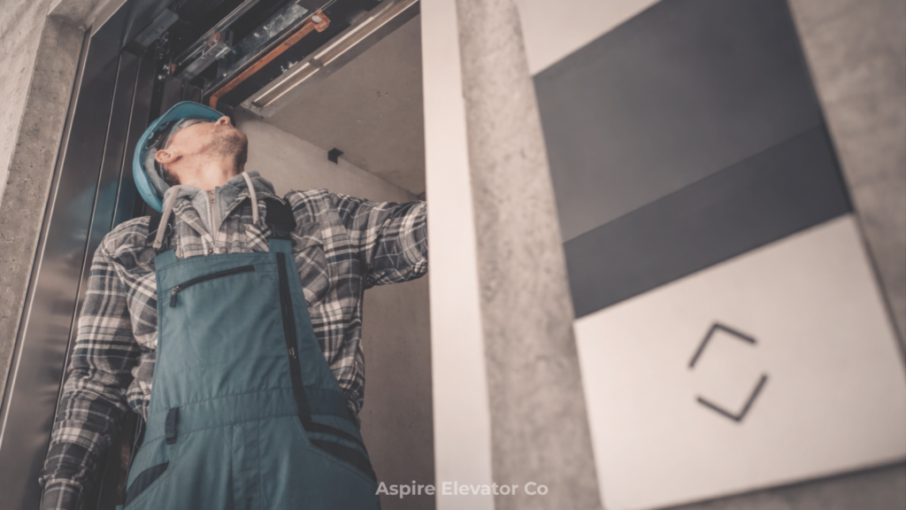 Elevator technician inspecting the interior of an elevator while standing inside the shaft, with control panel visible in the foreground
